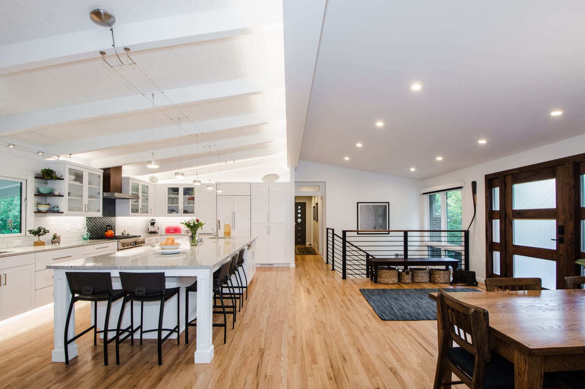 Applewood, CO renovation open kitchen with large island, white cabinets, and wood floors by Cillessen Construction