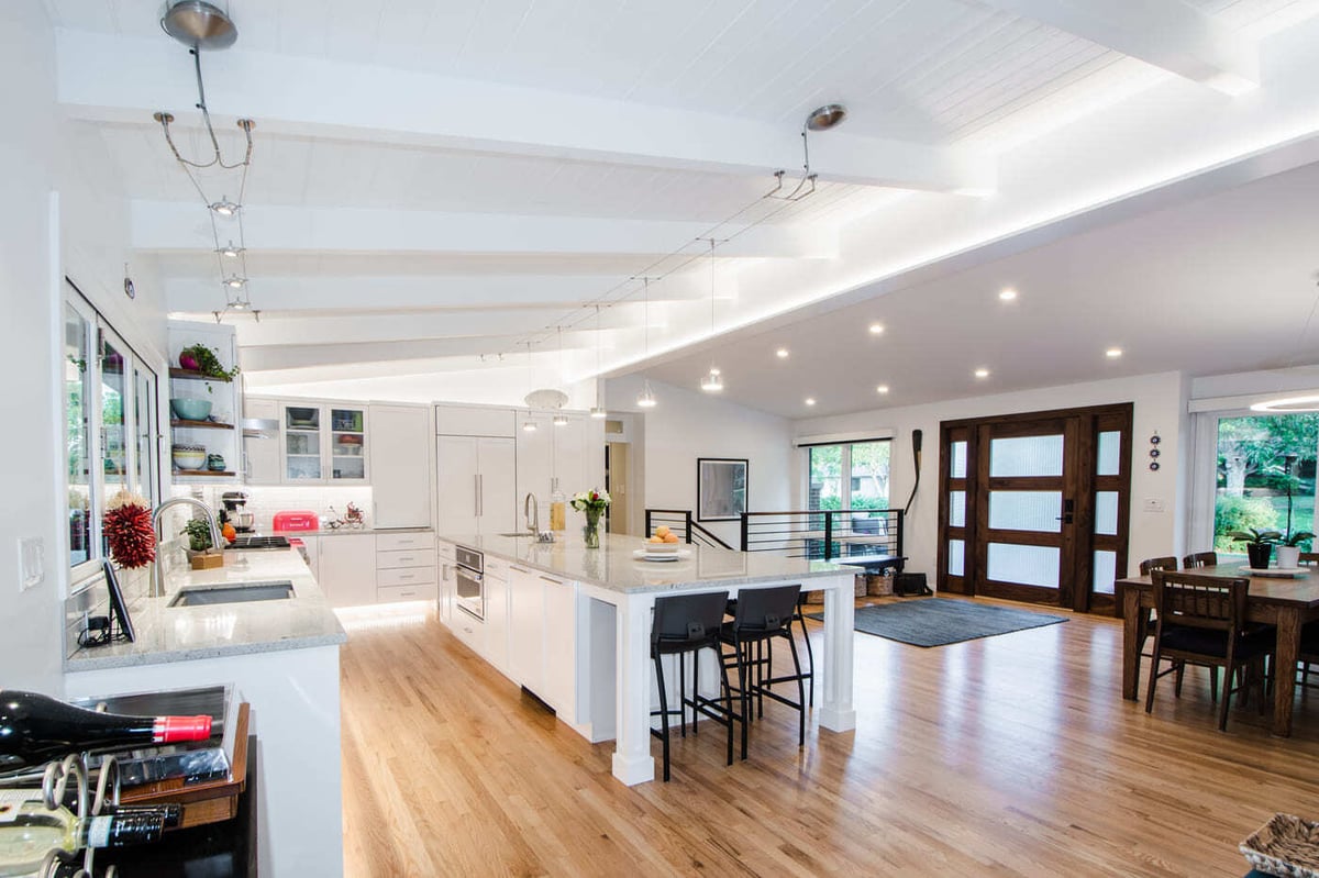 Applewood, CO renovation open kitchen with large island, wood floors, and modern lighting by Cillessen Construction