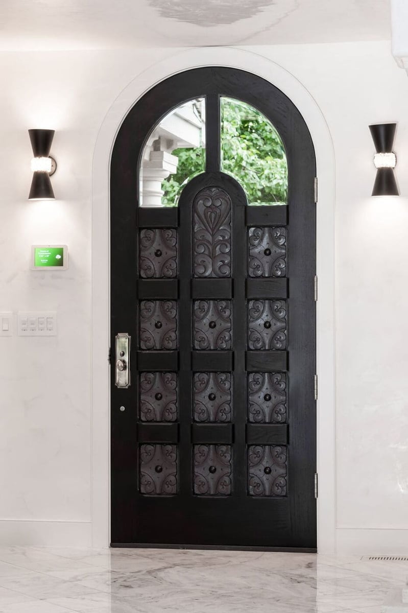 Greenwood Village, CO arched black front door with decorative iron panels by Cillessen Construction