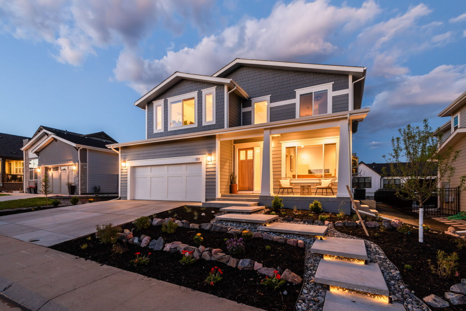 Angled exterior of custom home with illuminated porch and landscaped walkway in Louisville, CO by Cillessen Construction