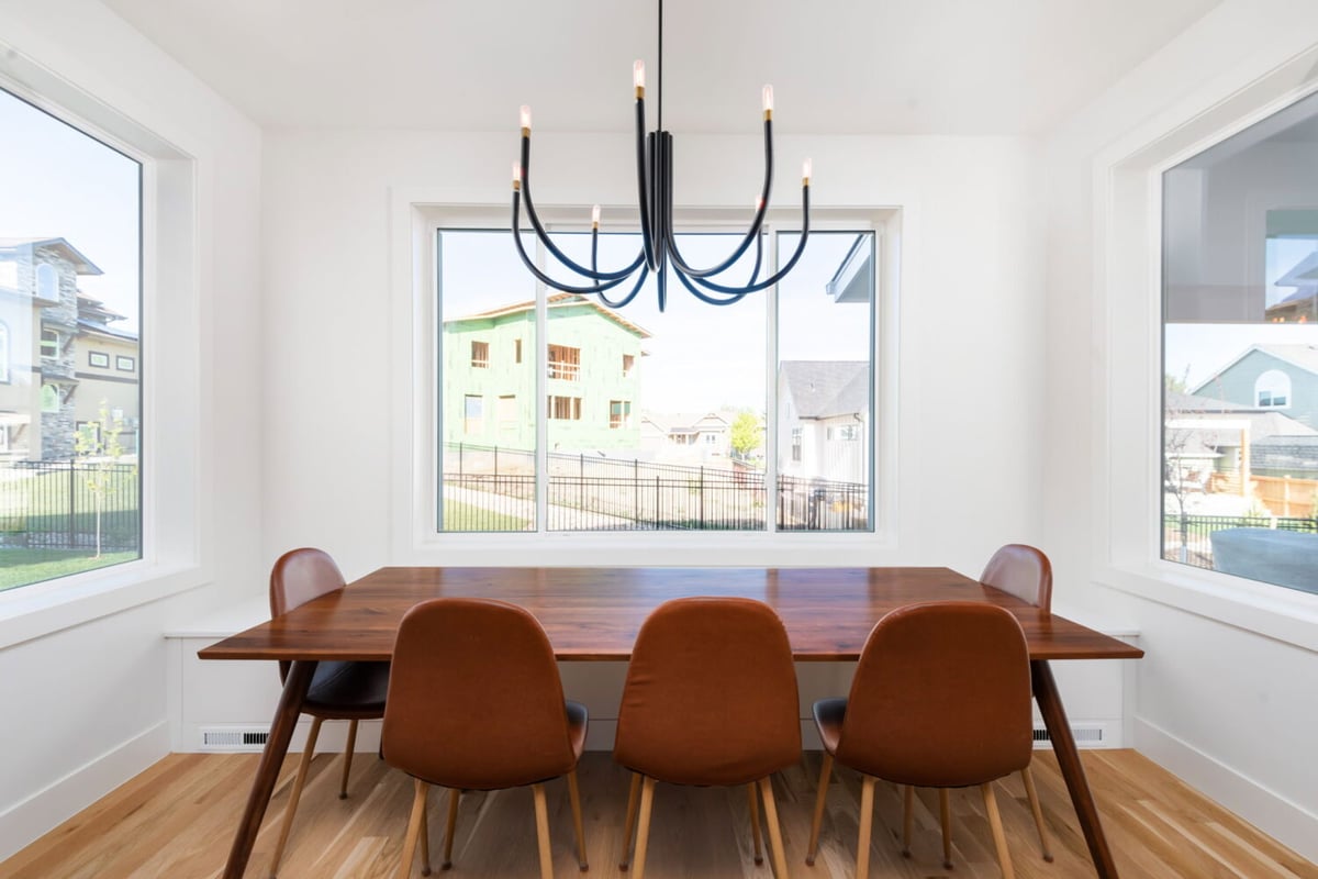 Bright dining area with modern chandelier and large windows in custom home in Louisville, CO by Cillessen Construction