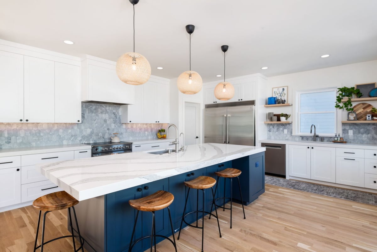 Bright kitchen with quartz island, bar seating, and white cabinetry in custom home in Louisville, CO by Cillessen Construction