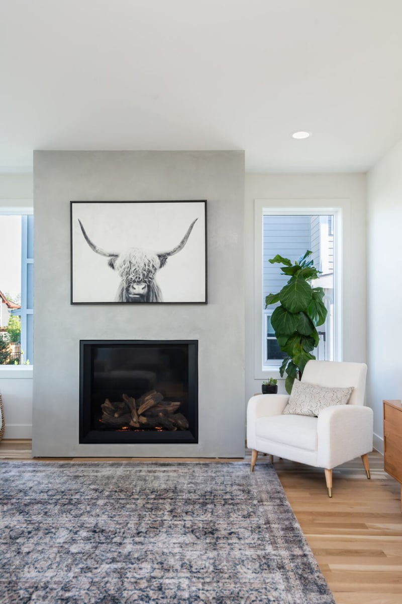 Close-up of modern fireplace with framed art and chair in custom home in Louisville, CO by Cillessen Construction