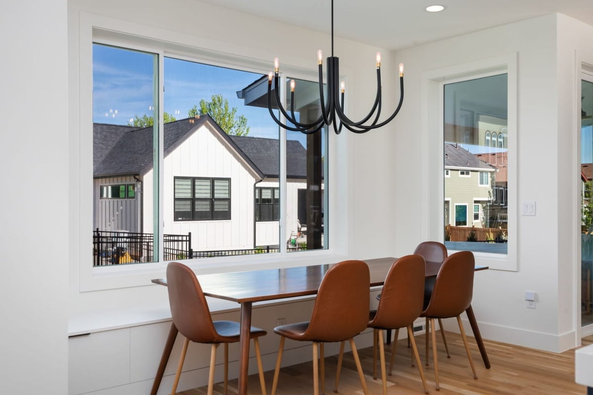Dining nook with wood table, leather chairs, and large windows in custom home in Louisville, CO by Cillessen Construction