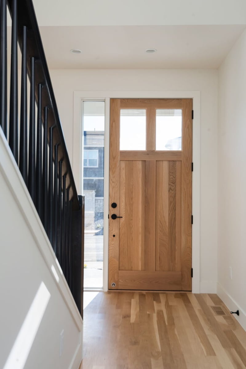 Entryway with wood front door and staircase in custom home in Louisville, CO by Cillessen Construction