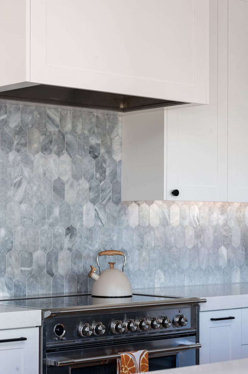 Kitchen range with tile backsplash and white cabinetry in custom home in Louisville, CO by Cillessen Construction