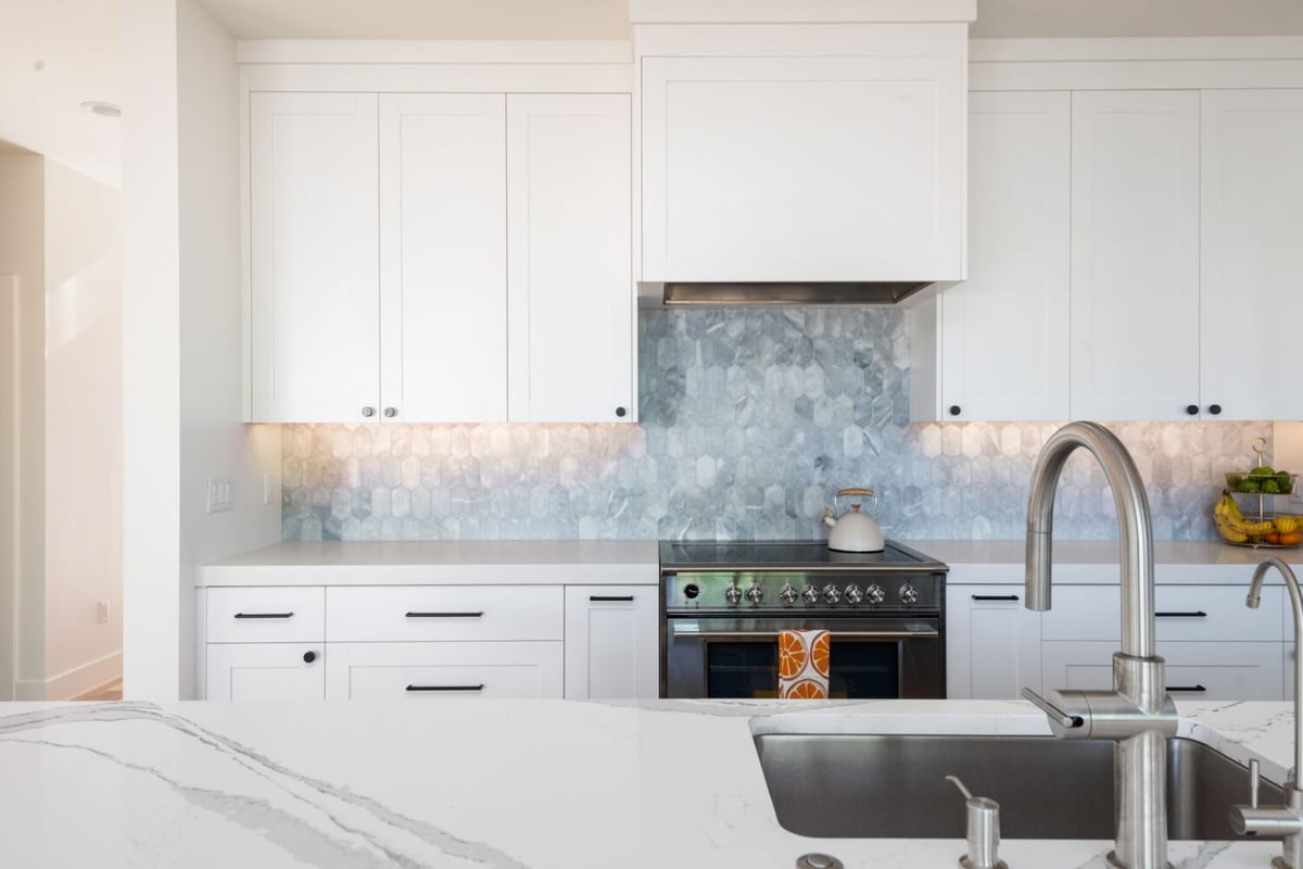 Kitchen with range, hex tile backsplash, and quartz counters in custom home in Louisville, CO by Cillessen Construction