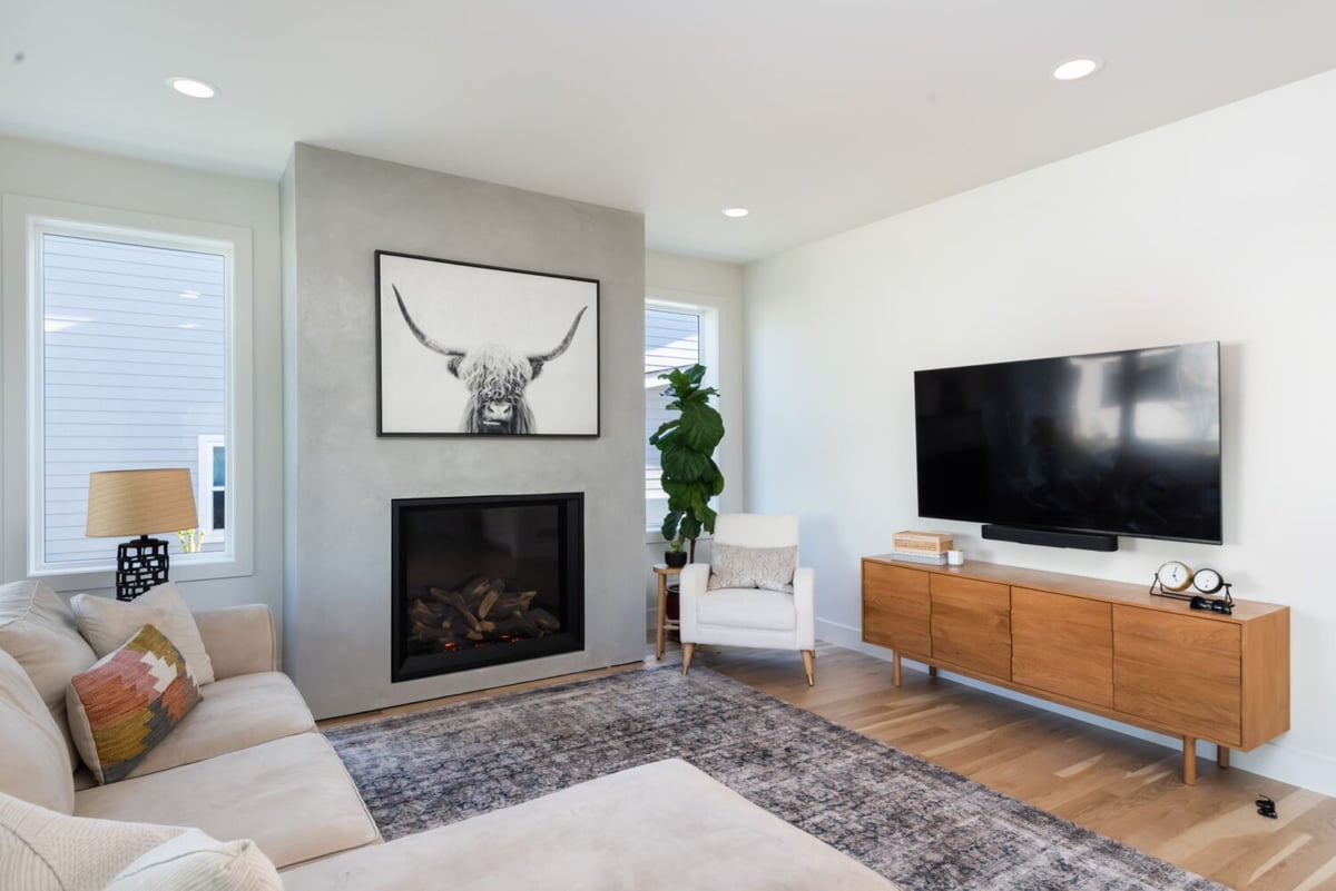 Living room with modern fireplace, wall art, and mounted TV in custom home in Louisville, CO by Cillessen Construction