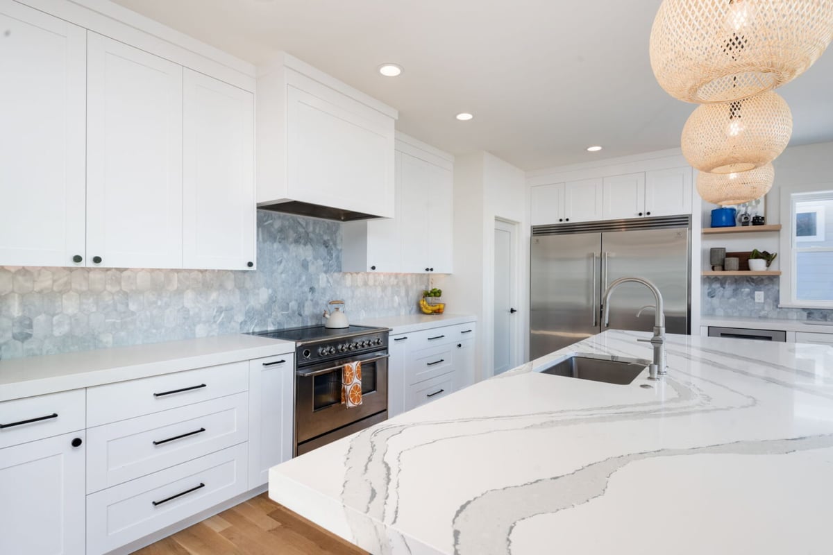 Modern kitchen with range, quartz counters, and white cabinets in custom home in Louisville, CO by Cillessen Construction