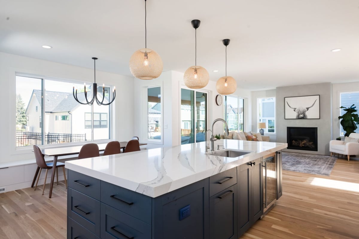Open kitchen with large island, pendant lights, and living area in custom home in Louisville, CO by Cillessen Construction
