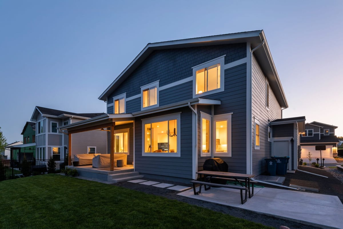 Rear exterior at dusk with lit windows and patio of custom home in Louisville, CO by Cillessen Construction