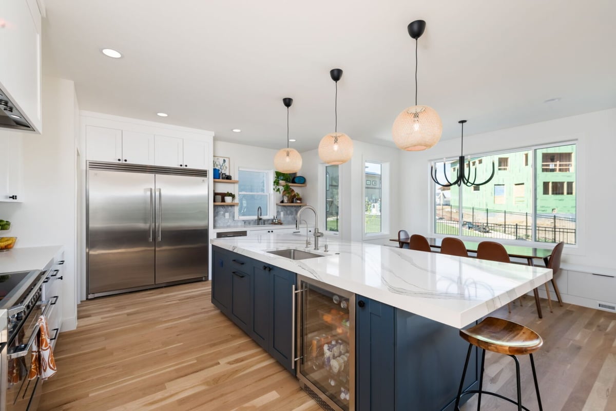 Wide kitchen view with island, wine fridge, and dining area in custom home in Louisville, CO by Cillessen Construction