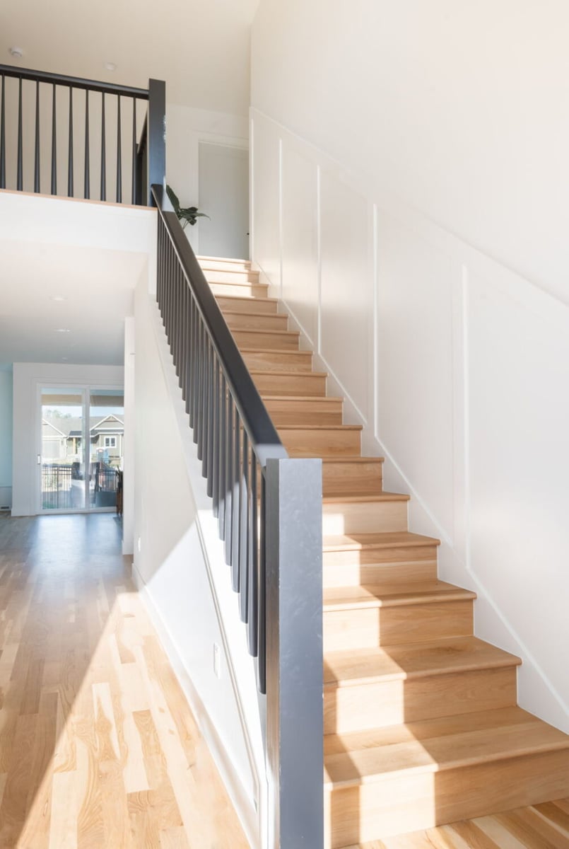 Wood staircase with black railing and natural light in custom home in Louisville, CO by Cillessen Construction