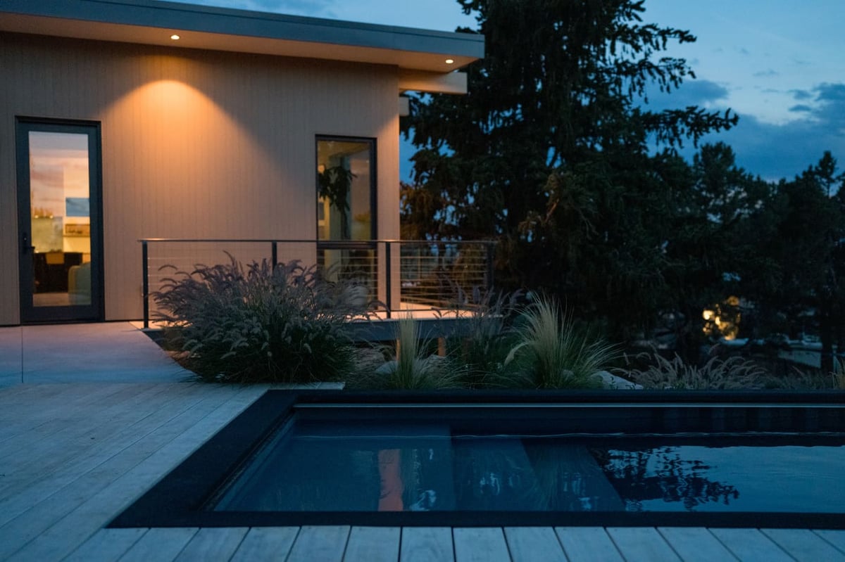 Backyard pool and deck at dusk with landscape lighting in Arvada, CO pop top renovation by Cillessen Construction