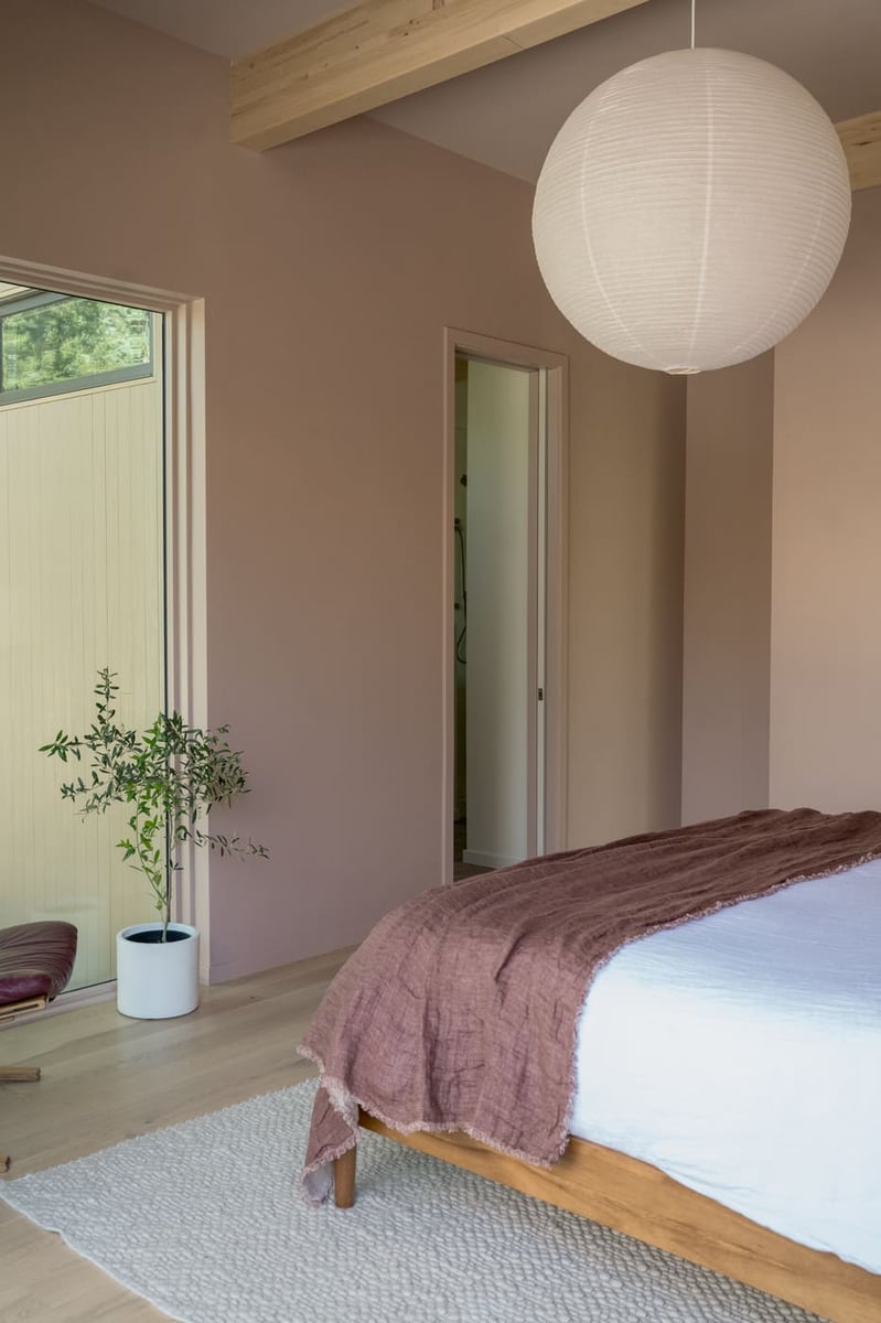 Bedroom with blush walls, wood beams, and paper pendant in Arvada, CO pop top renovation by Cillessen Construction