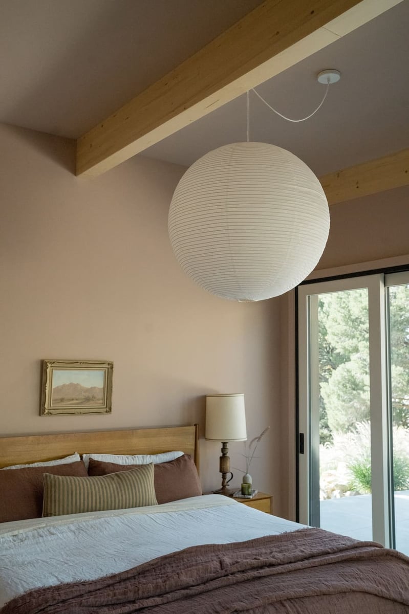 Bedroom with exposed beams and large pendant light in Arvada, CO pop top renovation by Cillessen Construction