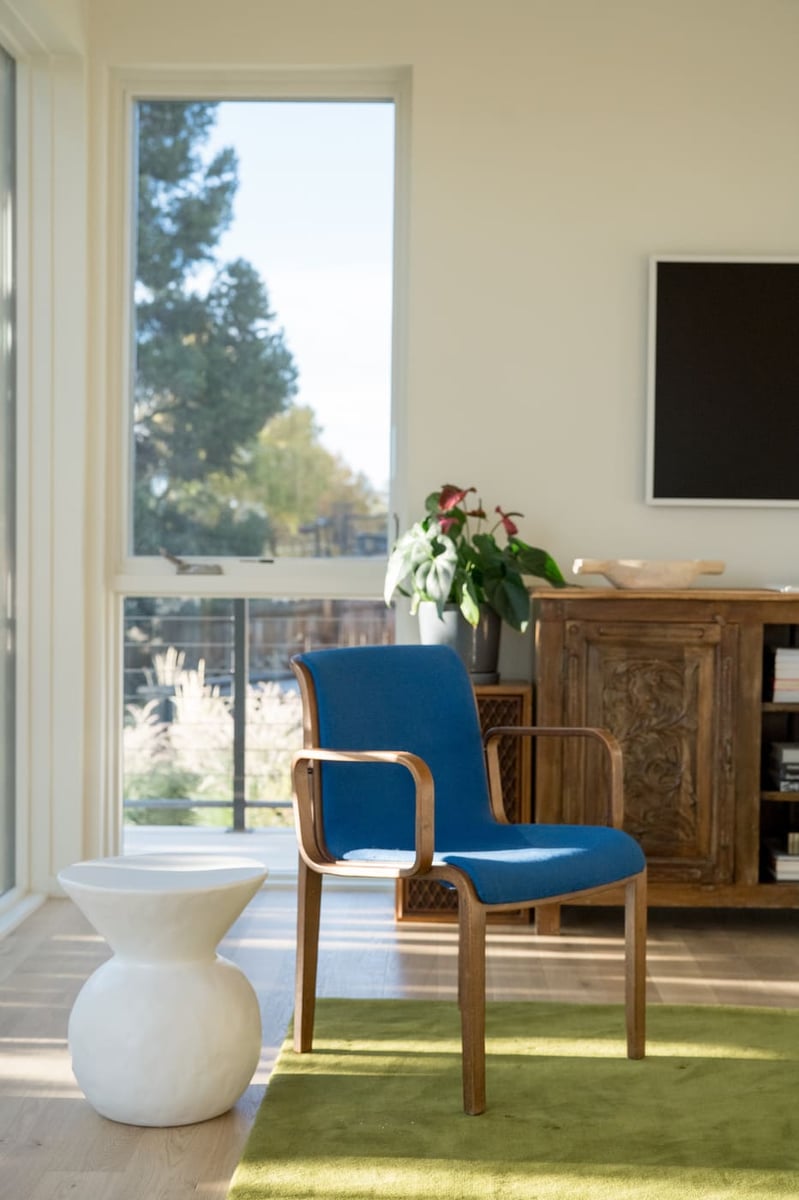 Blue accent chair and white side table by large window in Arvada, CO pop top renovation by Cillessen Construction