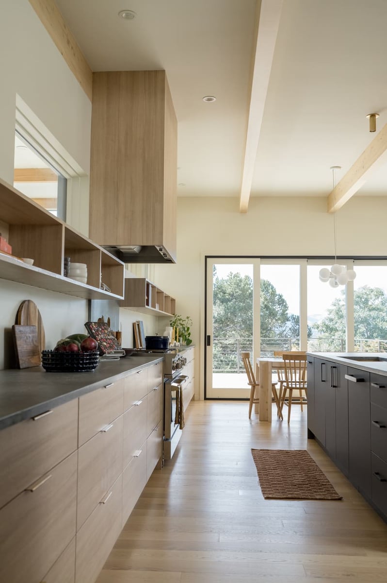 Bright kitchen with long counter, open shelving, and view to dining area in Arvada, CO pop top renovation by Cillessen Construction