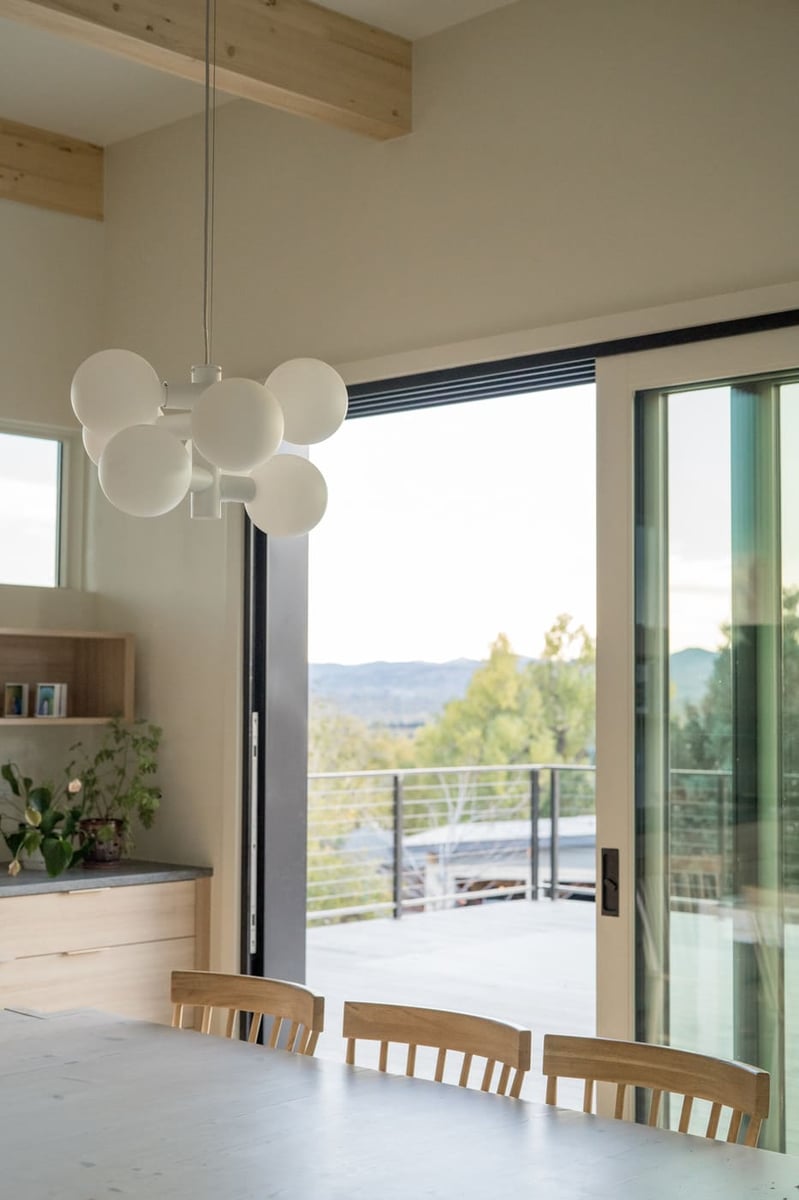 Dining area with modern pendant and sliding doors to deck in Arvada, CO pop top renovation by Cillessen Construction