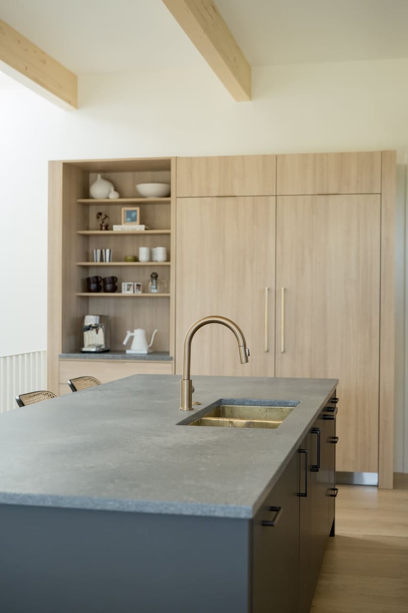 Kitchen island with integrated sink, brass faucet, and wood cabinetry in Arvada, CO pop top renovation by Cillessen Construction
