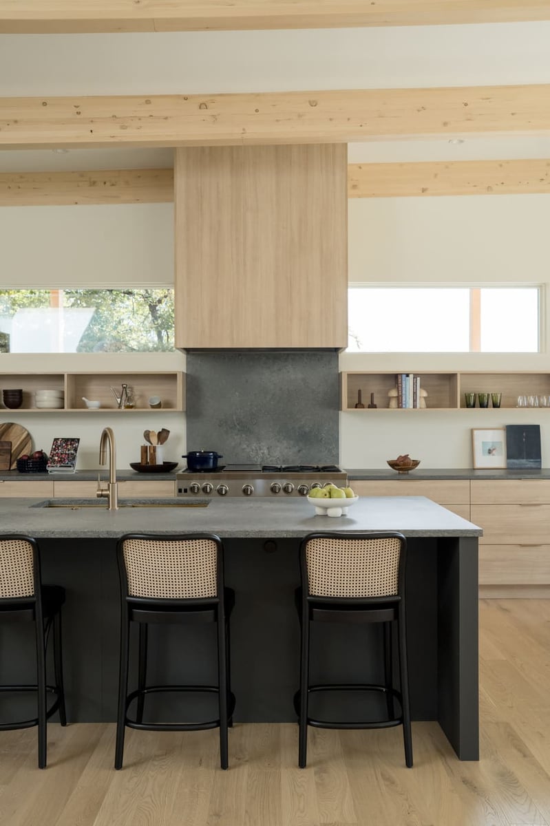 Kitchen island with seating, wood cabinetry, and range wall in Arvada, CO pop top renovation by Cillessen Construction