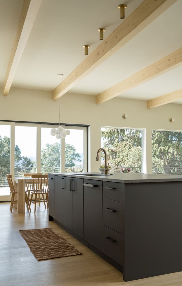 Kitchen island with sink and view to dining area in Arvada, CO pop top renovation by Cillessen Construction