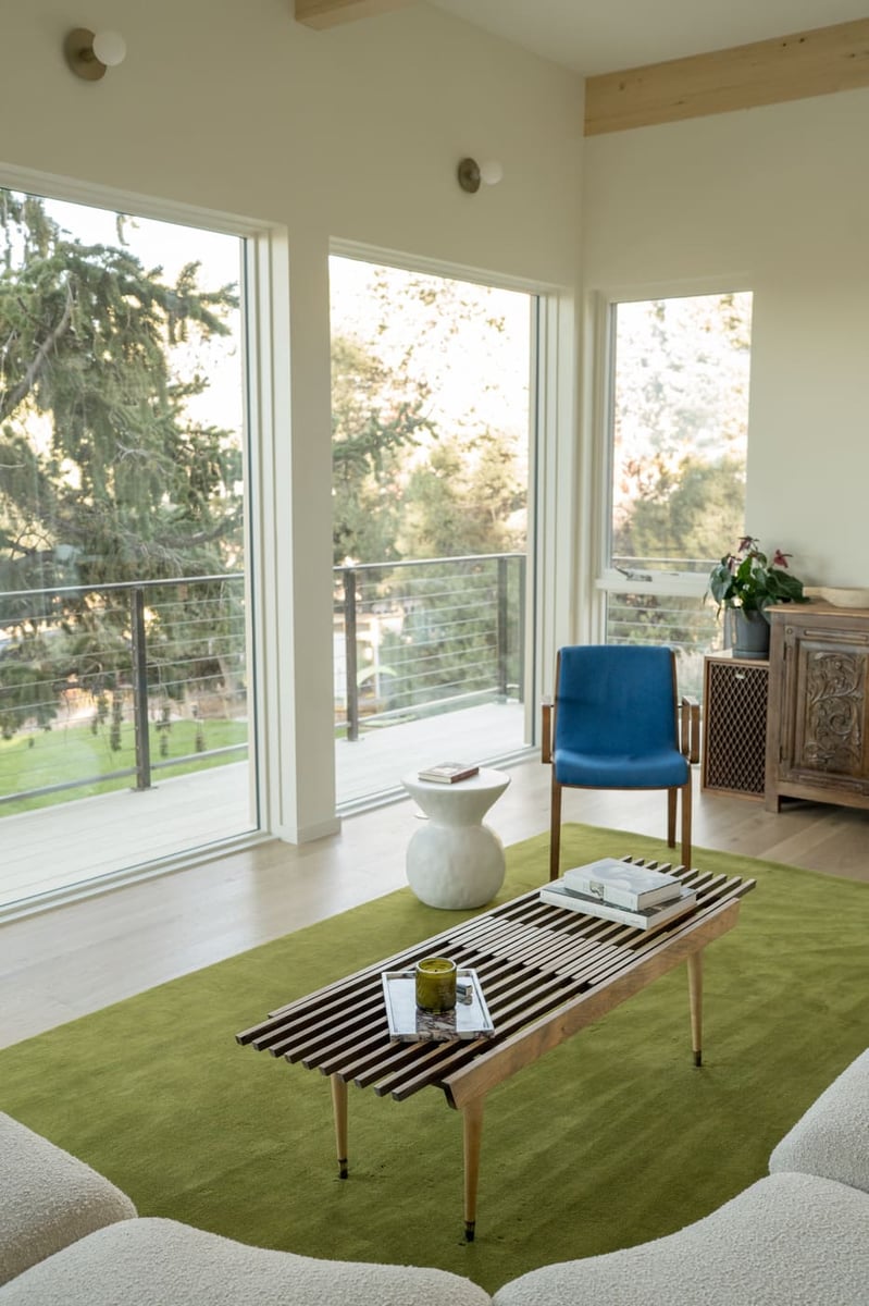 Living room with large windows, green rug, wood coffee table, and blue chair in Arvada, CO pop top renovation by Cillessen Construction