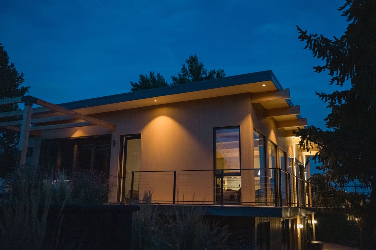 Modern home exterior at dusk with deck and warm lighting in Arvada, CO pop top renovation by Cillessen Construction
