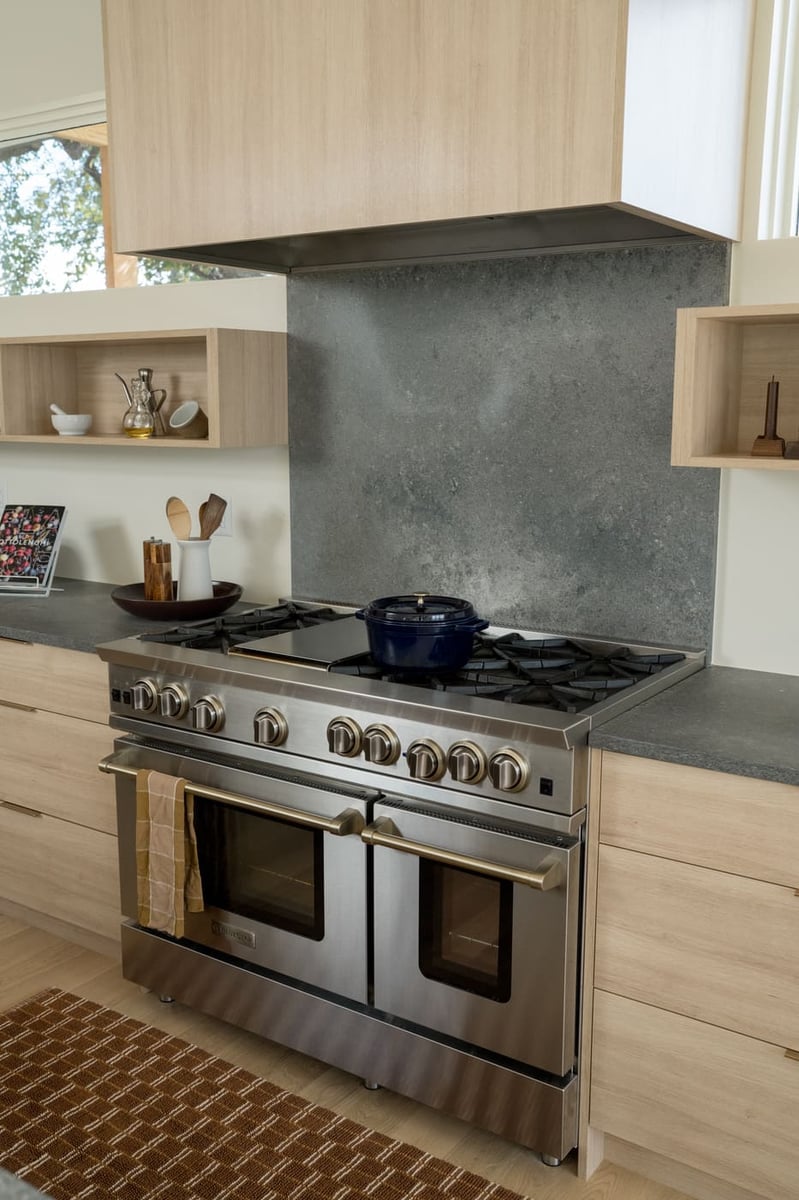 Modern kitchen with range, wood cabinets, and stone backsplash in Arvada, CO pop top renovation by Cillessen Construction