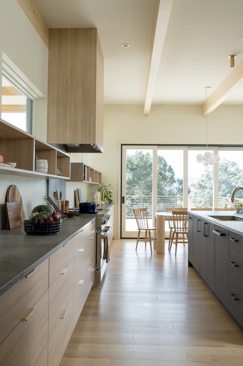 Modern kitchen with wood cabinetry, open shelving, and island leading to dining area in Arvada, CO pop top renovationby Cillessen Construction
