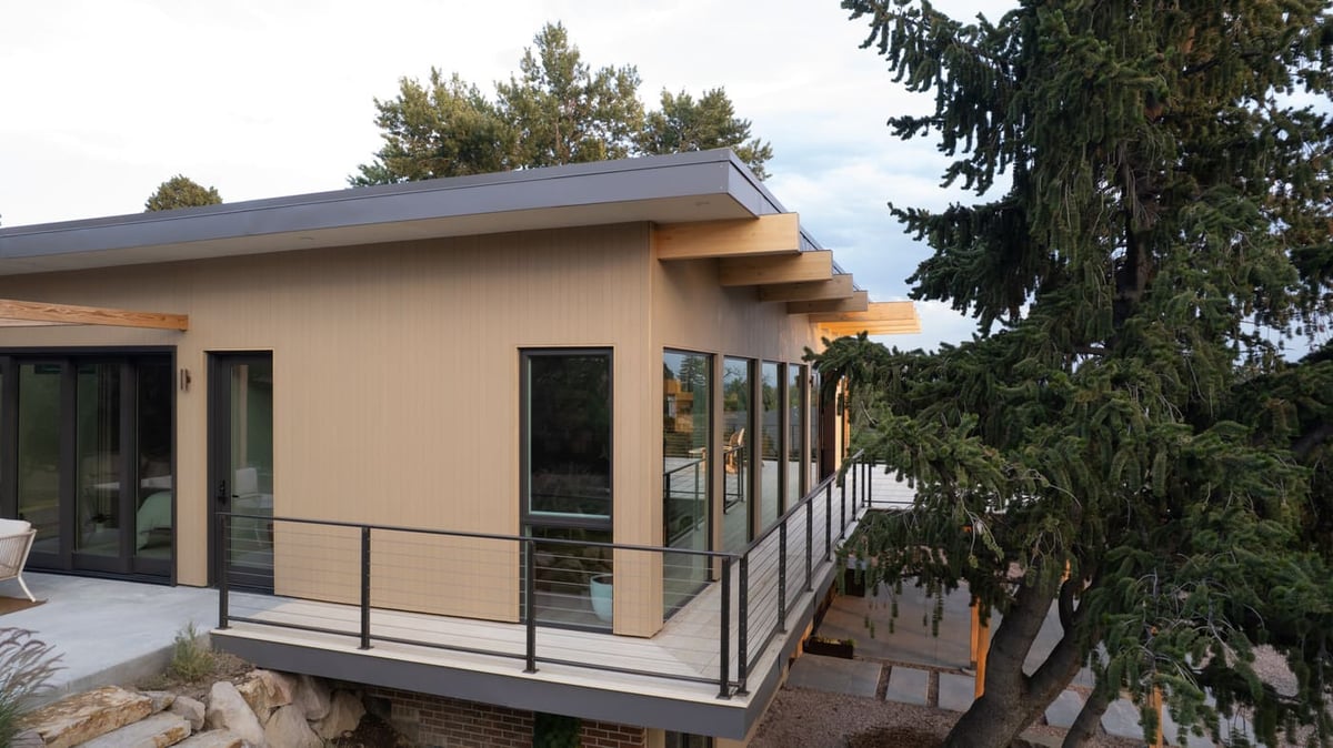 Side view of pop top renovation with deck railing and large windows in Arvada, CO by Cillessen Construction