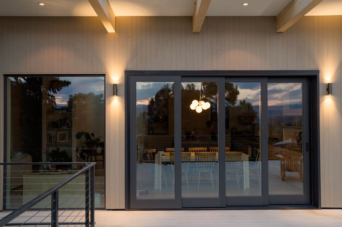 Sliding glass doors and deck with evening interior glow in Arvada, CO pop top renovation by Cillessen Construction