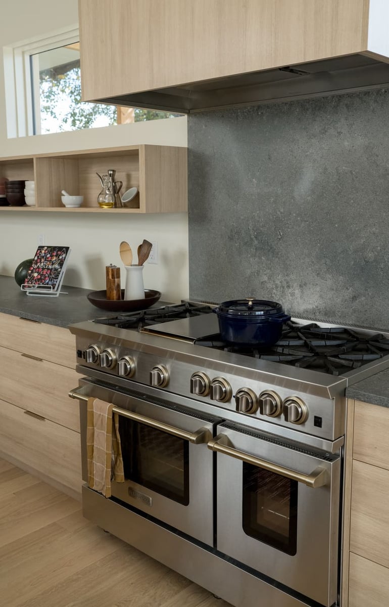 Stainless steel range with stone backsplash and wood cabinets in Arvada, CO pop top renovation by Cillessen Construction
