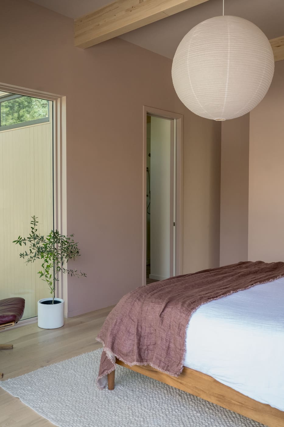 Bedroom with blush walls, wood beams, and paper pendant in Arvada, CO pop top renovation by Cillessen Construction