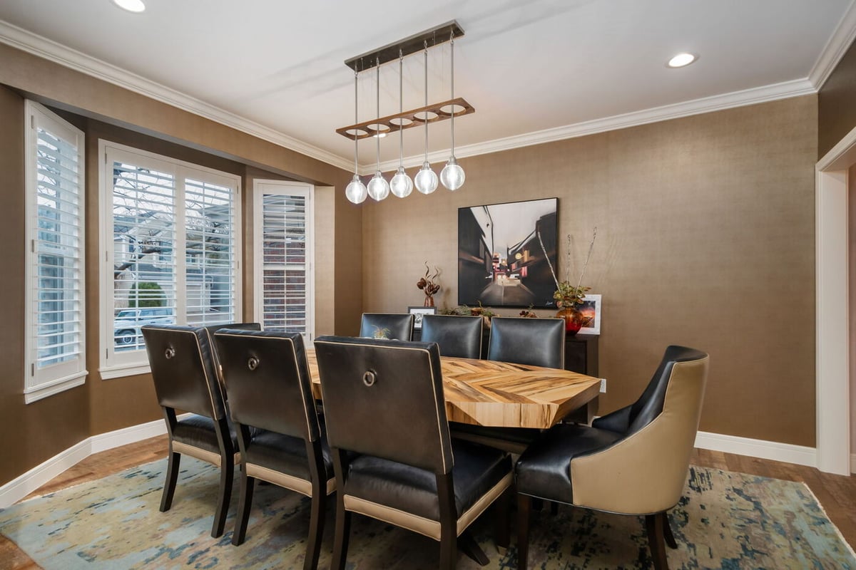 Littleton, CO whole home renovation dining room with wood table, leather chairs, and modern pendant lighting by Cillessen Construction
