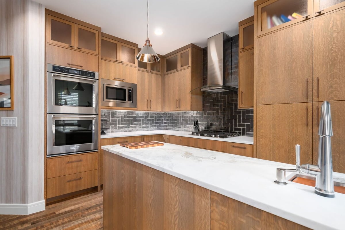 Littleton, CO whole home renovation kitchen with quartz island, built-in appliances, and tile backsplash by Cillessen Construction.