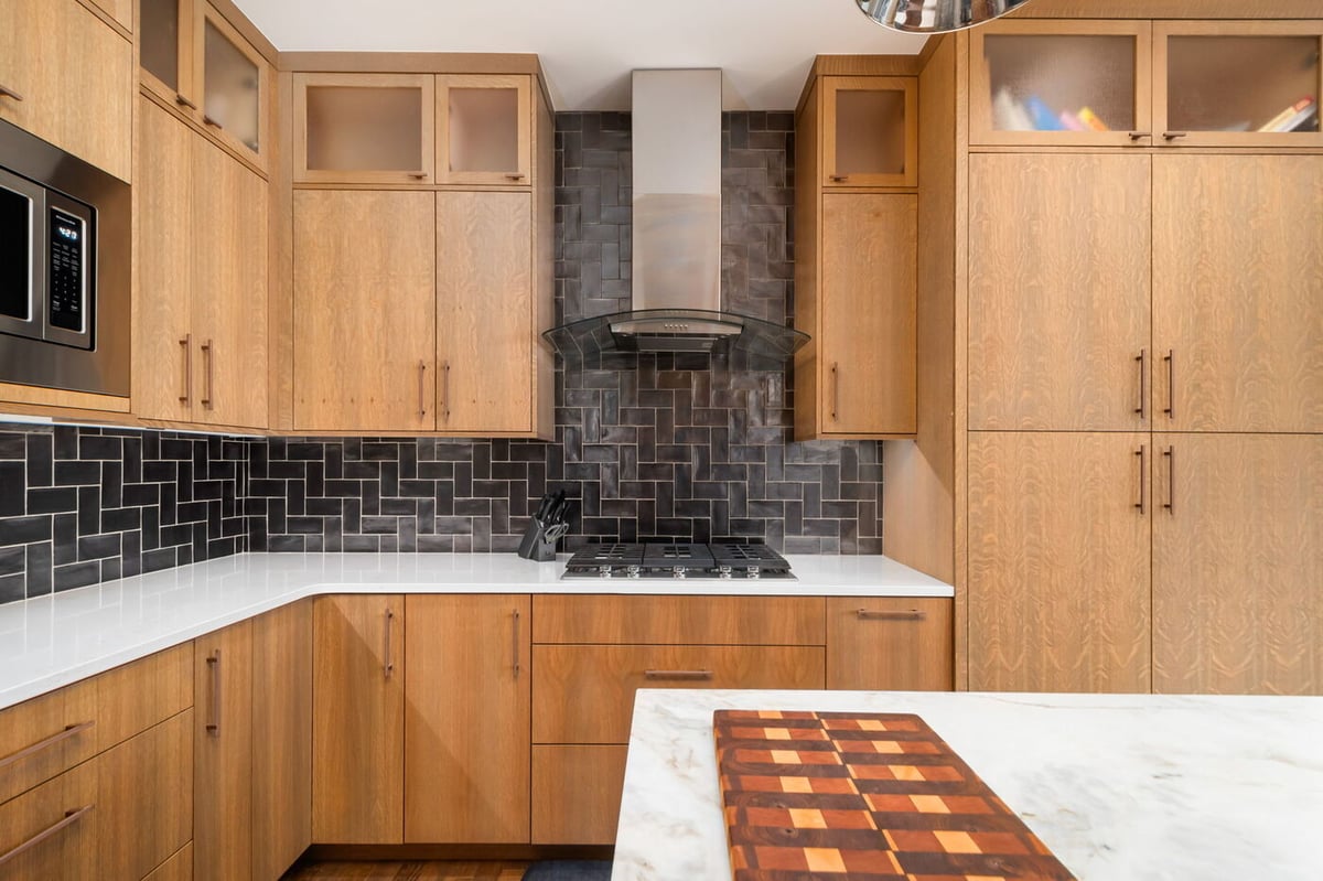 Littleton, CO whole home renovation kitchen with wood cabinets, tile backsplash, and modern range hood by Cillessen Construction
