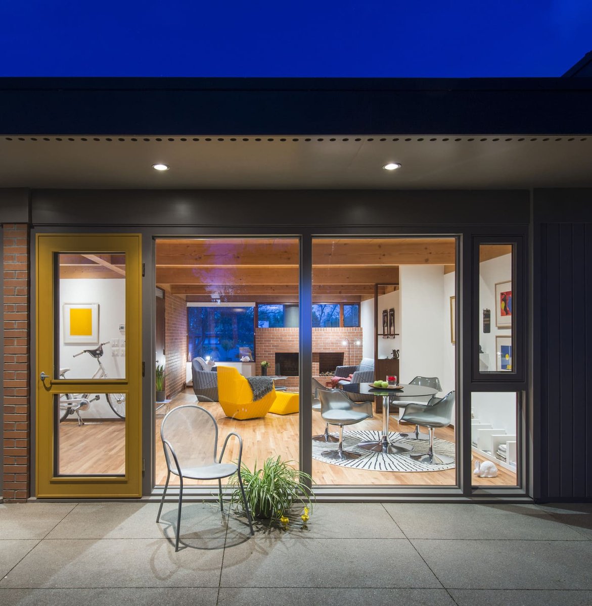 Applewood, CO custom home evening view through glass showing modern interior and patio by Cillessen Construction
