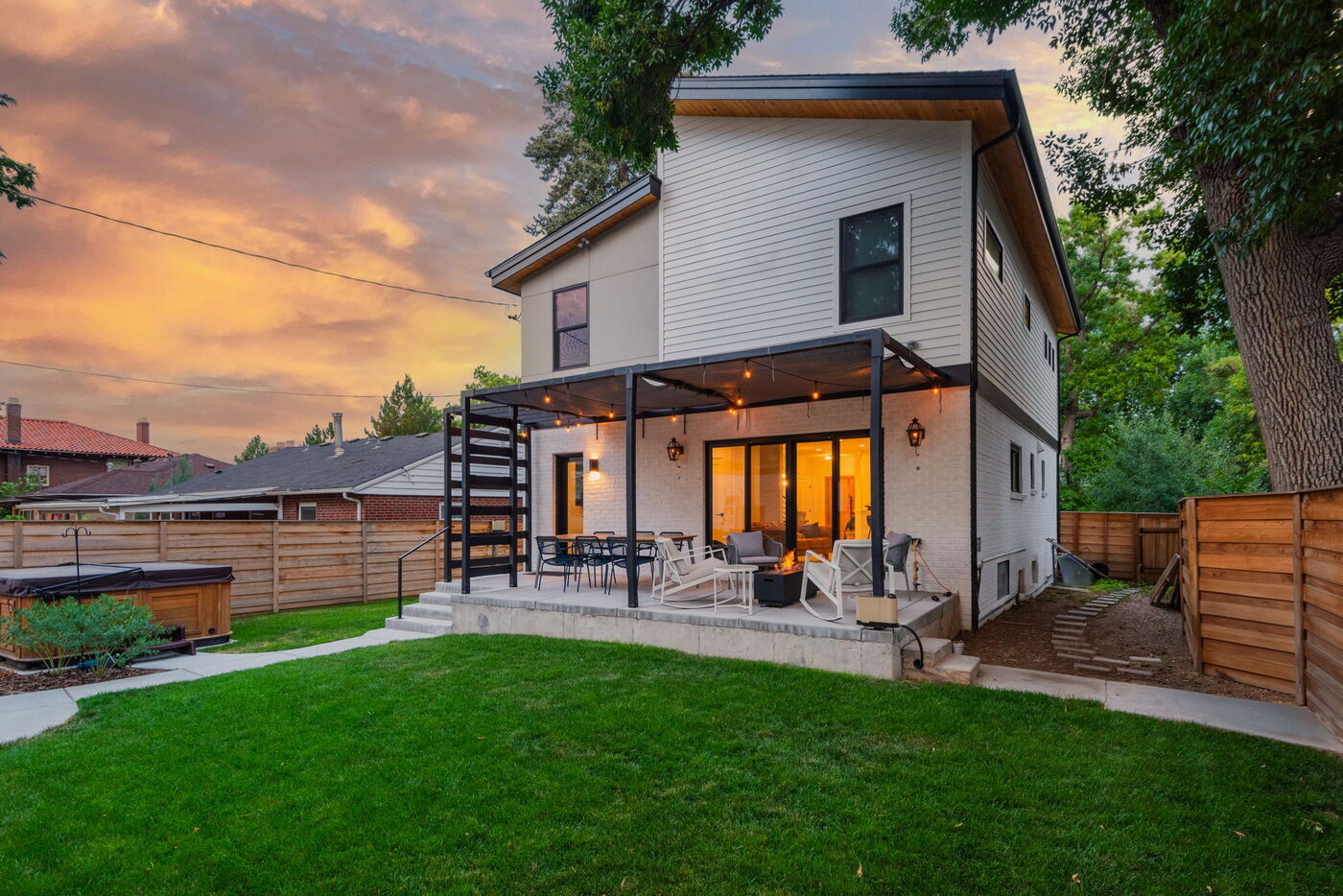 Denver pop top renovation backyard with covered patio, dining area, and string lights at sunset by Cillessen Construction